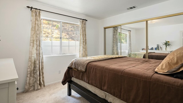 bedroom with a closet, visible vents, light colored carpet, and baseboards