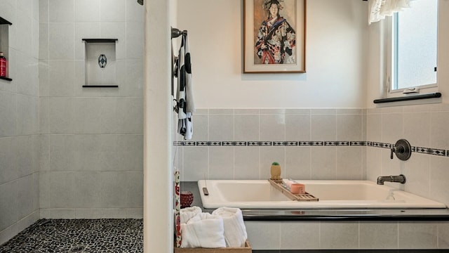 full bathroom featuring a garden tub and a tile shower