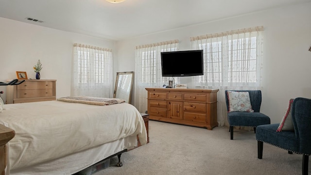 bedroom with visible vents, light colored carpet, and multiple windows