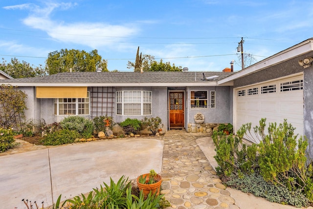 ranch-style home with a shingled roof, a garage, and stucco siding