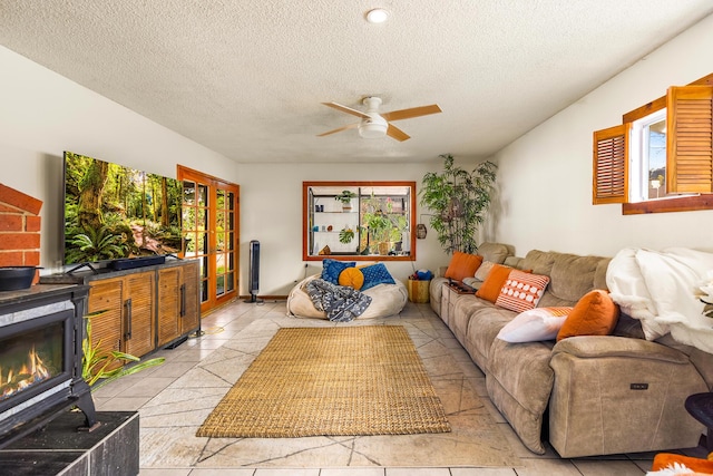 living area featuring a textured ceiling, light tile patterned floors, a fireplace, and ceiling fan