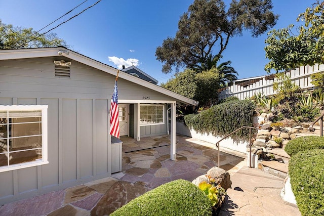 view of property exterior featuring a patio area, board and batten siding, and fence