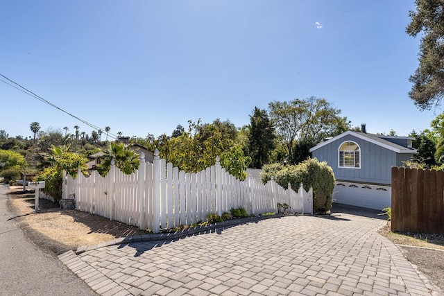 exterior space with decorative driveway, a garage, and fence