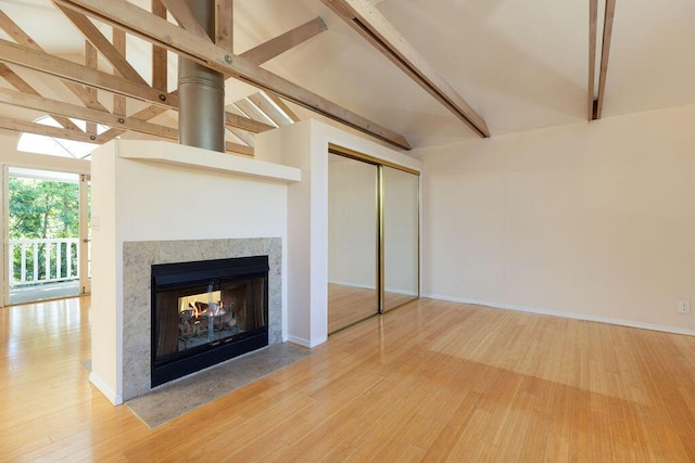 unfurnished living room featuring vaulted ceiling with beams, wood finished floors, a multi sided fireplace, and baseboards