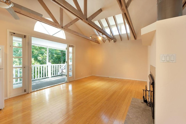 unfurnished living room featuring beamed ceiling, high vaulted ceiling, light wood-style floors, baseboards, and ceiling fan