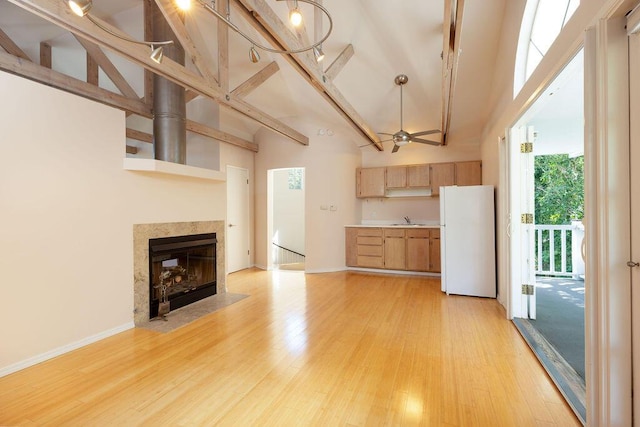 unfurnished living room with light wood-type flooring, a towering ceiling, and a sink