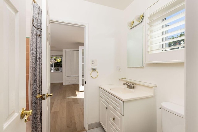 bathroom with toilet, wood finished floors, and vanity