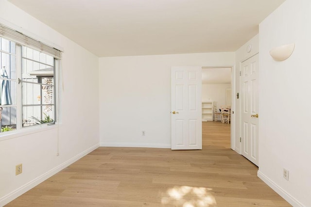 unfurnished room with light wood-style flooring and baseboards