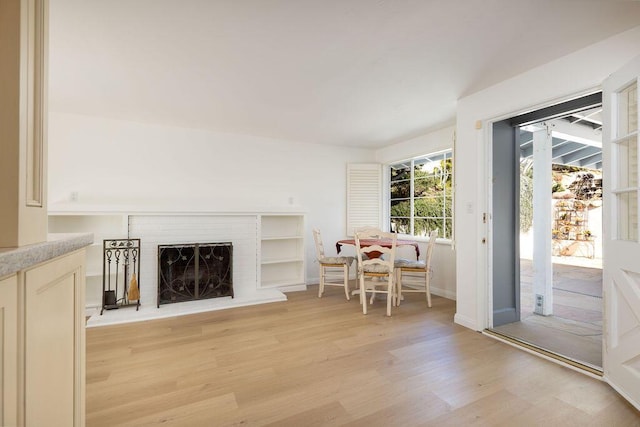 living room featuring light wood-style flooring, a fireplace, and baseboards