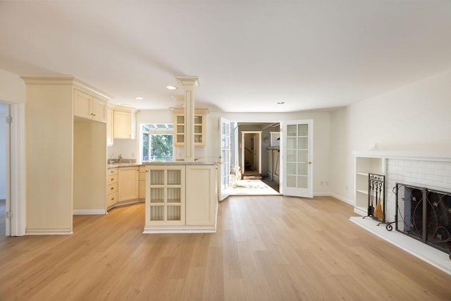 unfurnished living room featuring a brick fireplace, french doors, light wood-type flooring, and baseboards