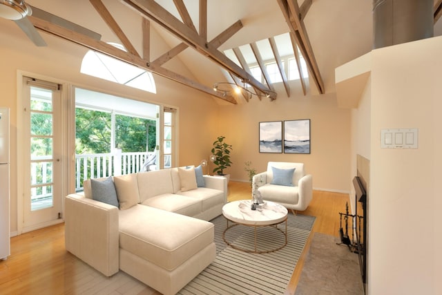 living area featuring a wealth of natural light, light wood-type flooring, beam ceiling, and ceiling fan