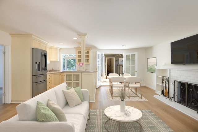 living room featuring recessed lighting, a fireplace, light wood-type flooring, and baseboards