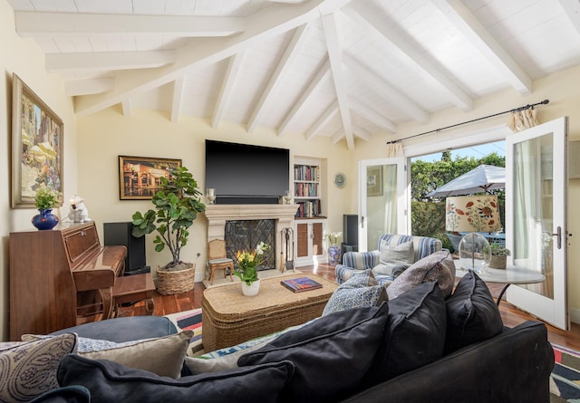 living room with a fireplace, lofted ceiling with beams, built in shelves, and wood finished floors