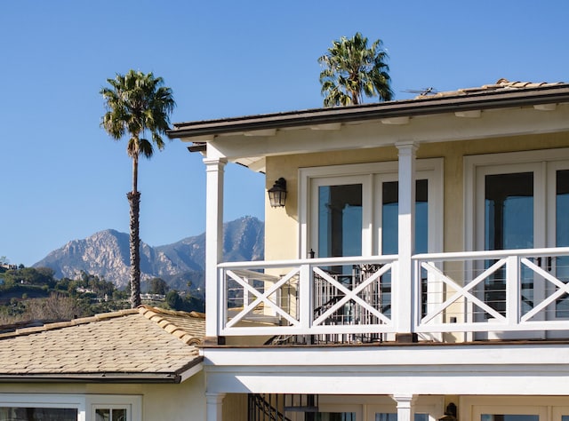 view of side of property with a mountain view, a balcony, stucco siding, and a tile roof