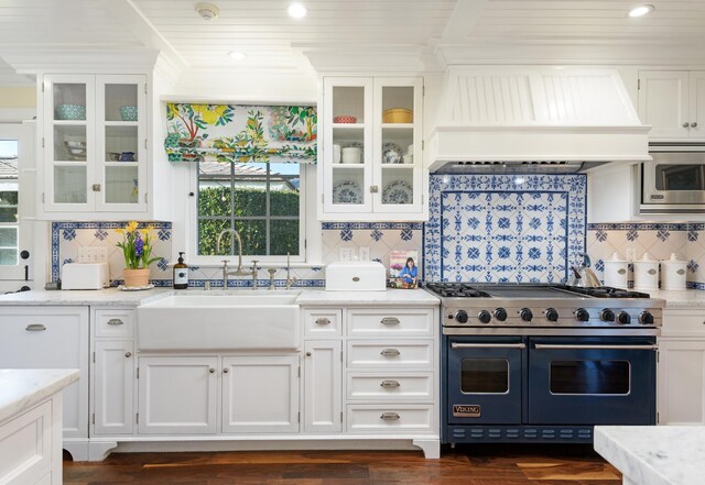 kitchen featuring built in microwave, double oven range, custom exhaust hood, white cabinets, and a sink