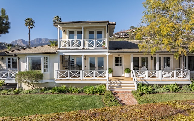 rear view of property featuring french doors, a balcony, a porch, and stucco siding