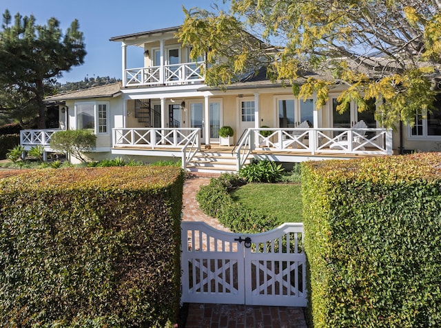 view of front of house with covered porch, a balcony, and stucco siding