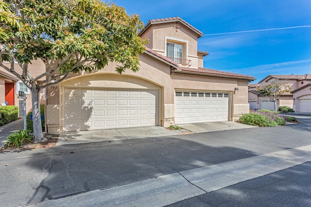 mediterranean / spanish home with stucco siding, a tiled roof, and a garage