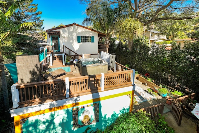 back of property featuring a deck, a hot tub, and stucco siding