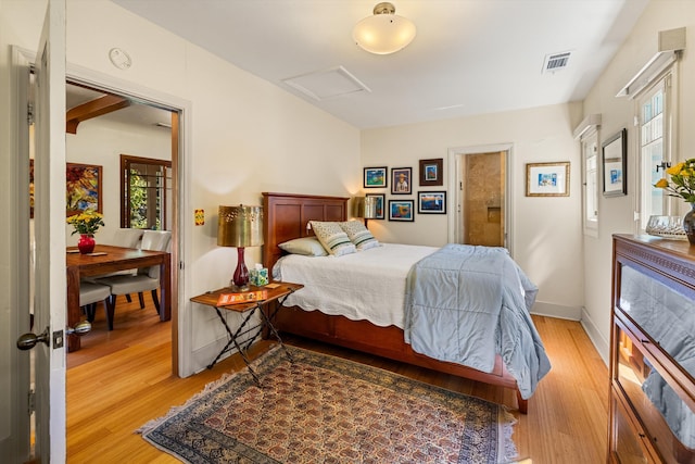 bedroom featuring attic access, light wood-style floors, visible vents, and baseboards