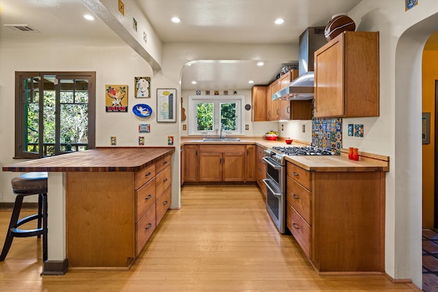 kitchen featuring range with two ovens, wood counters, arched walkways, and a sink