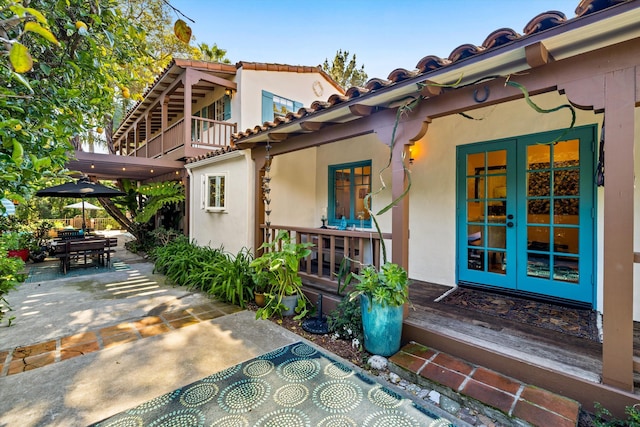 exterior space featuring a patio area, stucco siding, french doors, and a tile roof