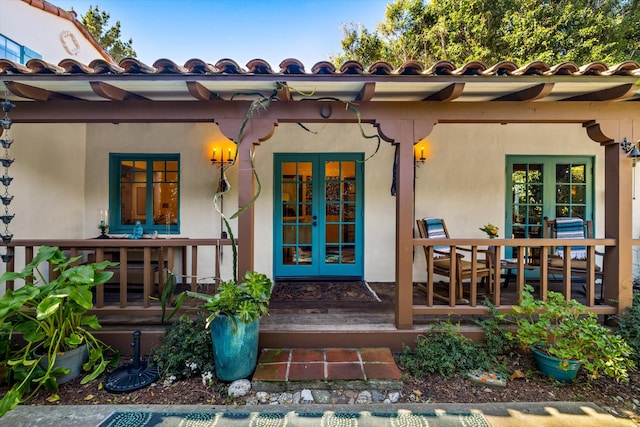 property entrance with a tiled roof, stucco siding, and french doors