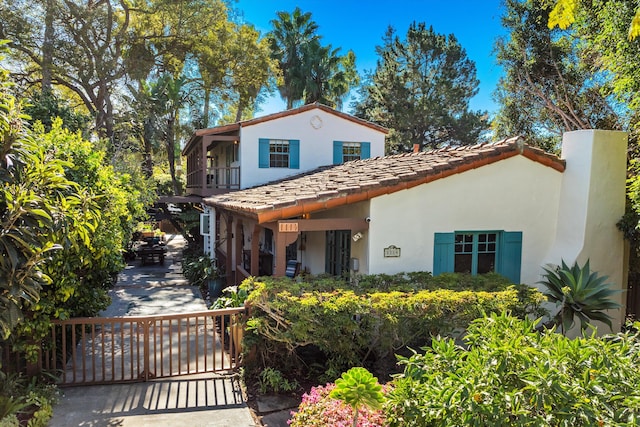 mediterranean / spanish-style home featuring a balcony, a gate, and stucco siding