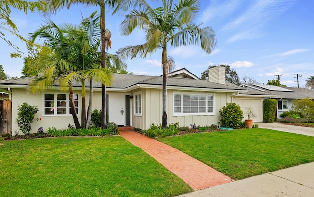 single story home featuring board and batten siding, a front lawn, a chimney, a garage, and driveway