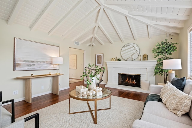 living room with a fireplace, lofted ceiling with beams, wood finished floors, and visible vents