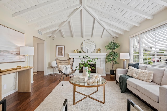 living room featuring vaulted ceiling with beams, baseboards, and wood finished floors