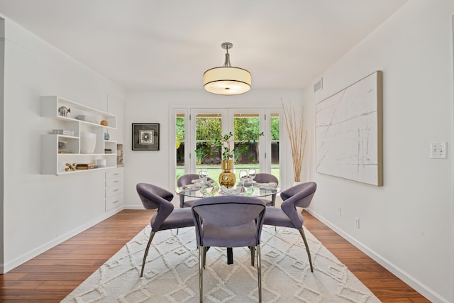 dining space with visible vents, baseboards, wood finished floors, and french doors