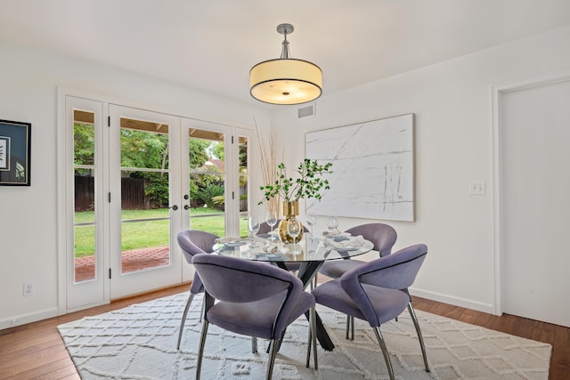 dining area with wood finished floors, visible vents, french doors, and baseboards