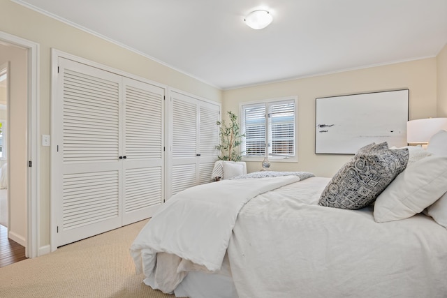 carpeted bedroom featuring crown molding and multiple closets