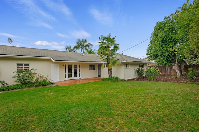 rear view of house with fence, stucco siding, french doors, a yard, and a patio