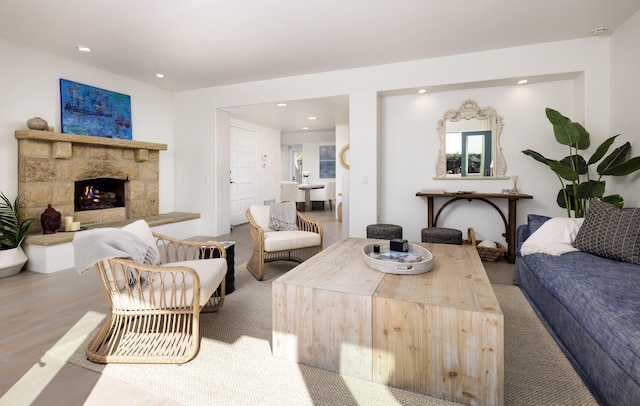 living room with recessed lighting, a stone fireplace, and wood finished floors