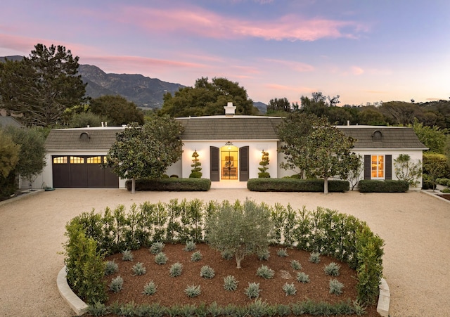 view of property with driveway, a tile roof, french doors, a mountain view, and a garage