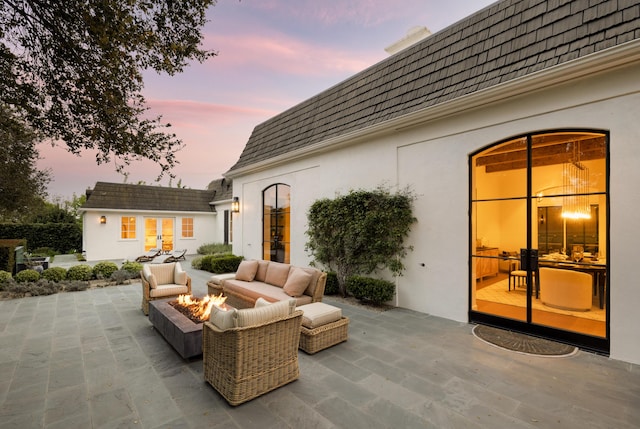 patio terrace at dusk featuring an outbuilding, an exterior structure, an outdoor hangout area, and french doors