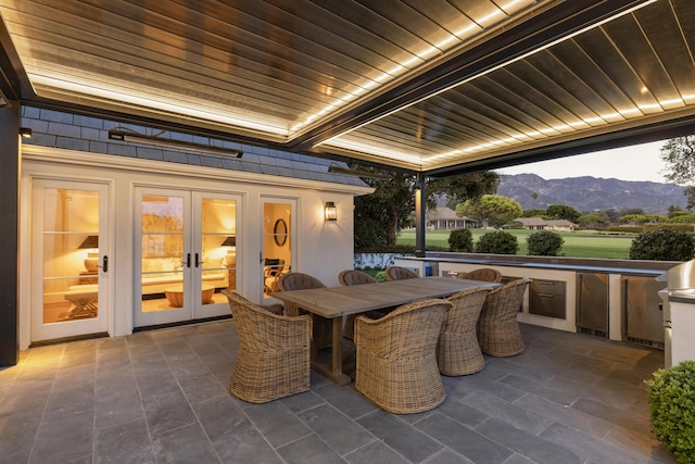 view of patio with a mountain view, french doors, and outdoor dining space