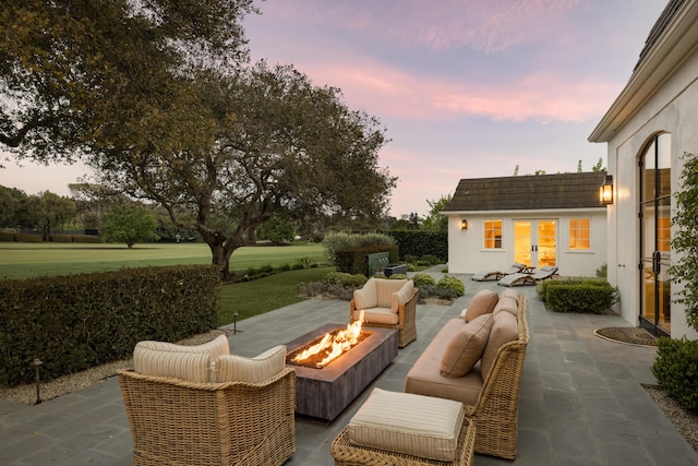 patio terrace at dusk with an outbuilding and an outdoor living space with a fire pit