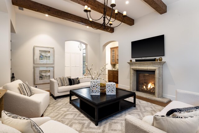 living area with beam ceiling, a notable chandelier, recessed lighting, a lit fireplace, and baseboards