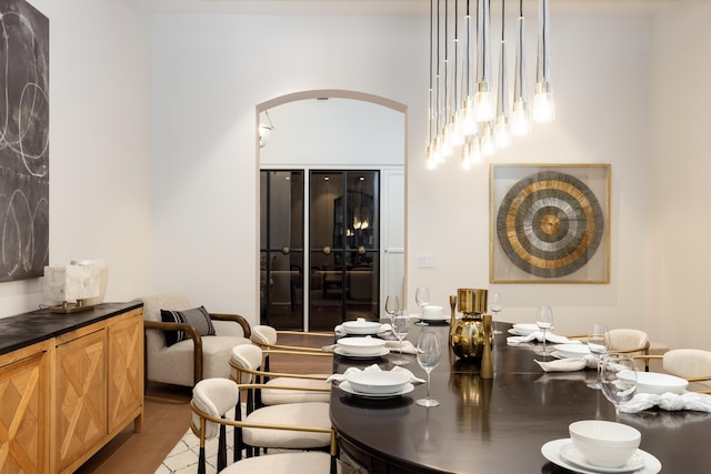 dining space featuring arched walkways and wood finished floors