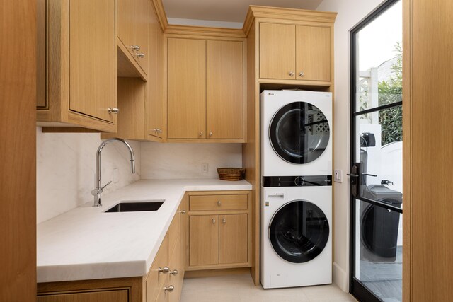 laundry room featuring a sink, cabinet space, and stacked washer and clothes dryer