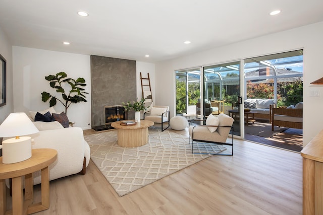 living room featuring recessed lighting, light wood-style flooring, a fireplace, and a sunroom