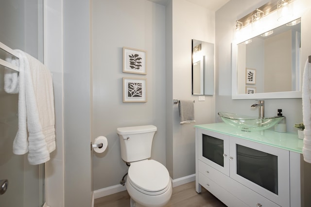 bathroom with vanity, toilet, wood finished floors, and baseboards