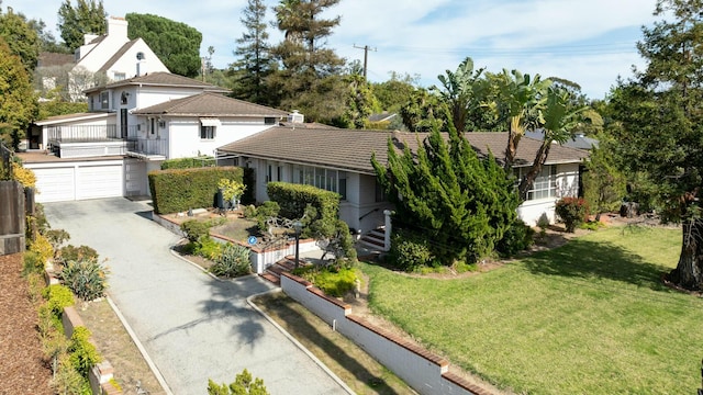 view of front facade with a garage, a tiled roof, and a front lawn