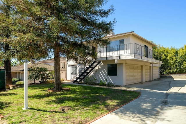 view of front of house featuring stairway, a front yard, stucco siding, a garage, and driveway