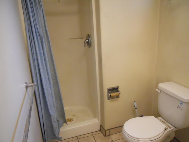 bathroom featuring tile patterned flooring, a shower stall, and toilet