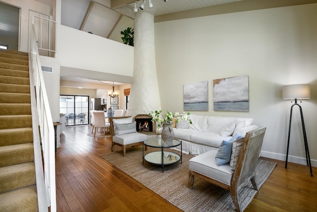 living area with visible vents, baseboards, stairs, an inviting chandelier, and hardwood / wood-style flooring