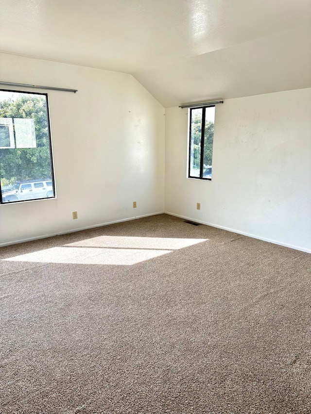 unfurnished room with vaulted ceiling, baseboards, visible vents, and carpet floors